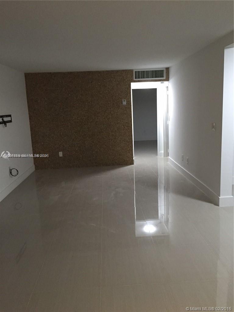 An empty room features glossy light-colored tile flooring and a textured cork accent wall — 4110 NW 79th Ave # 1B, Doral FL 33166, DORAL, FL
