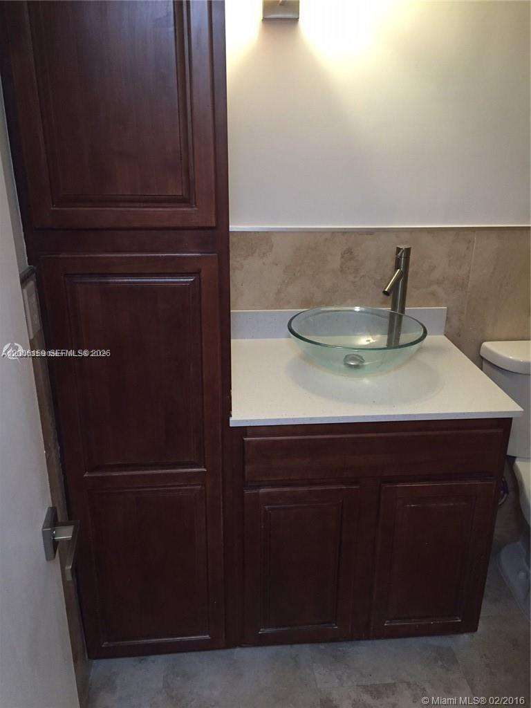 A bathroom features a tall wooden cabinet, a white vanity, and a glass vessel sink — 4110 NW 79th Ave # 1B, Doral FL 33166, DORAL, FL