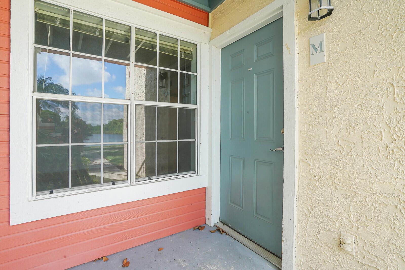 A teal front door with a letter M sign sits beside a large grid window — 1385 Crystal Way # M, Delray Beach FL 33444, DELRAY BEACH, FL