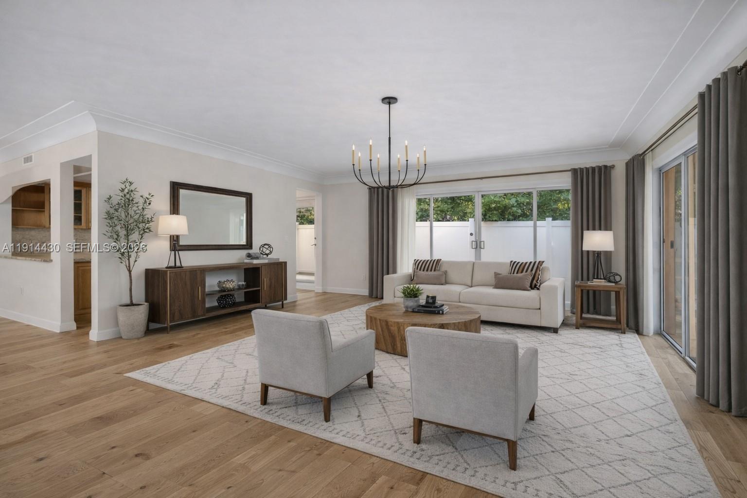 A living room features light wood floors, a beige sofa, two armchairs, and a chandelier — 700 NE 118th St, Biscayne Park FL 33161, BISCAYNE PARK, FL