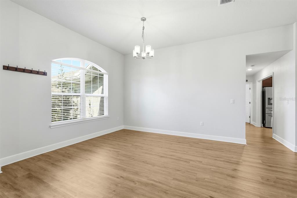An empty dining room with light wood flooring, a chandelier, and a large arched window — 120 BREN MAR LANE, PALM COAST, FL