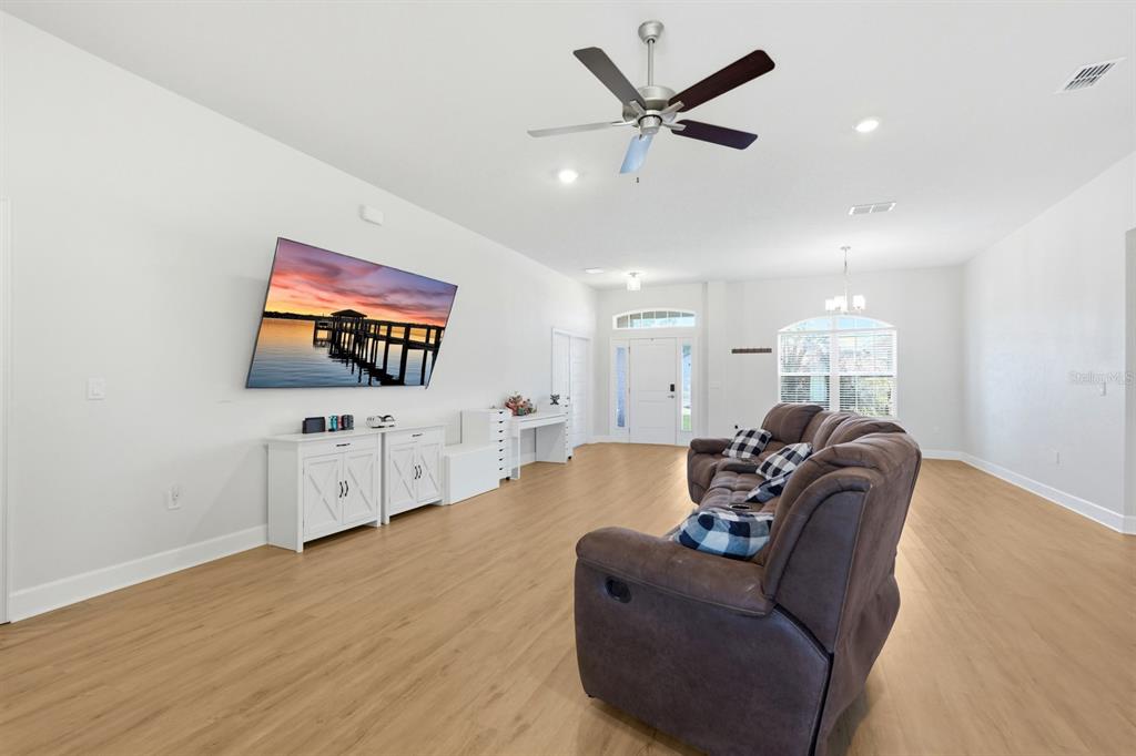 A living room features light wood-look flooring, a mounted television, and a brown reclining sofa — 120 BREN MAR LANE, PALM COAST, FL