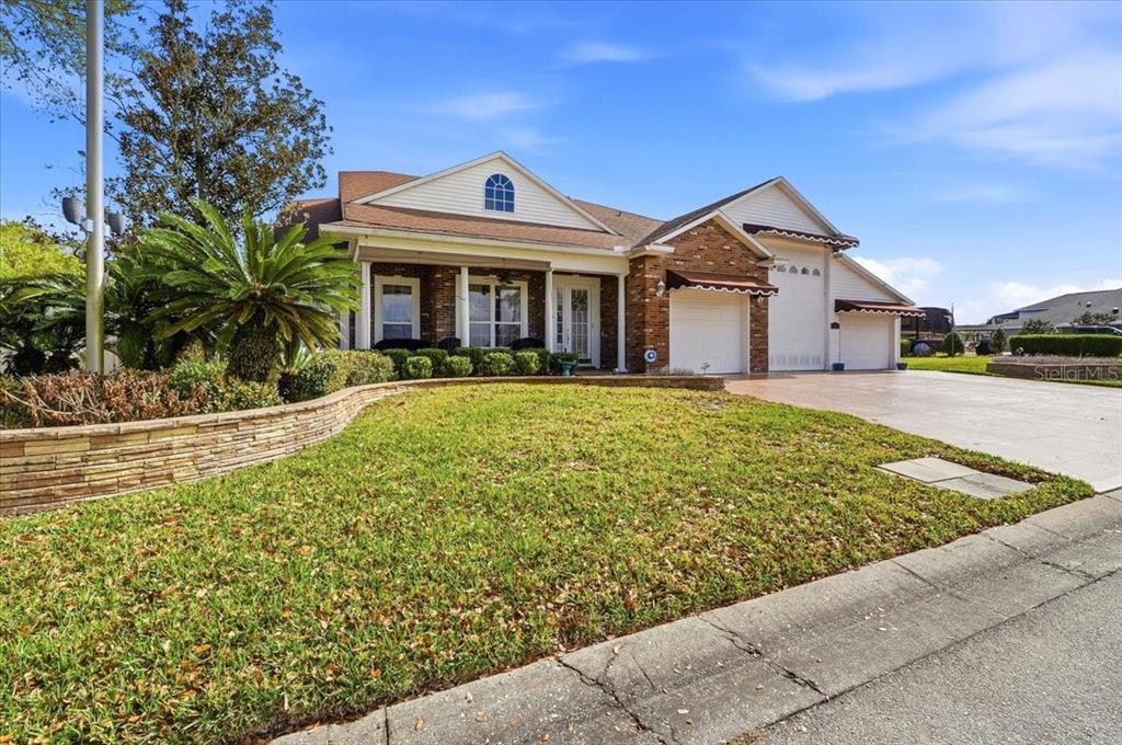 A single-story brick house with a multi-car garage and a landscaped front yard — 305 MOTORCOACH DRIVE S, POLK CITY, FL