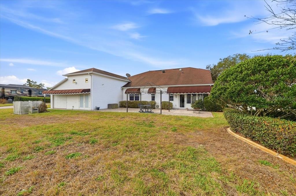 The exterior of a white house features a brown roof, patio, and a metal gazebo — 305 MOTORCOACH DRIVE S, POLK CITY, FL