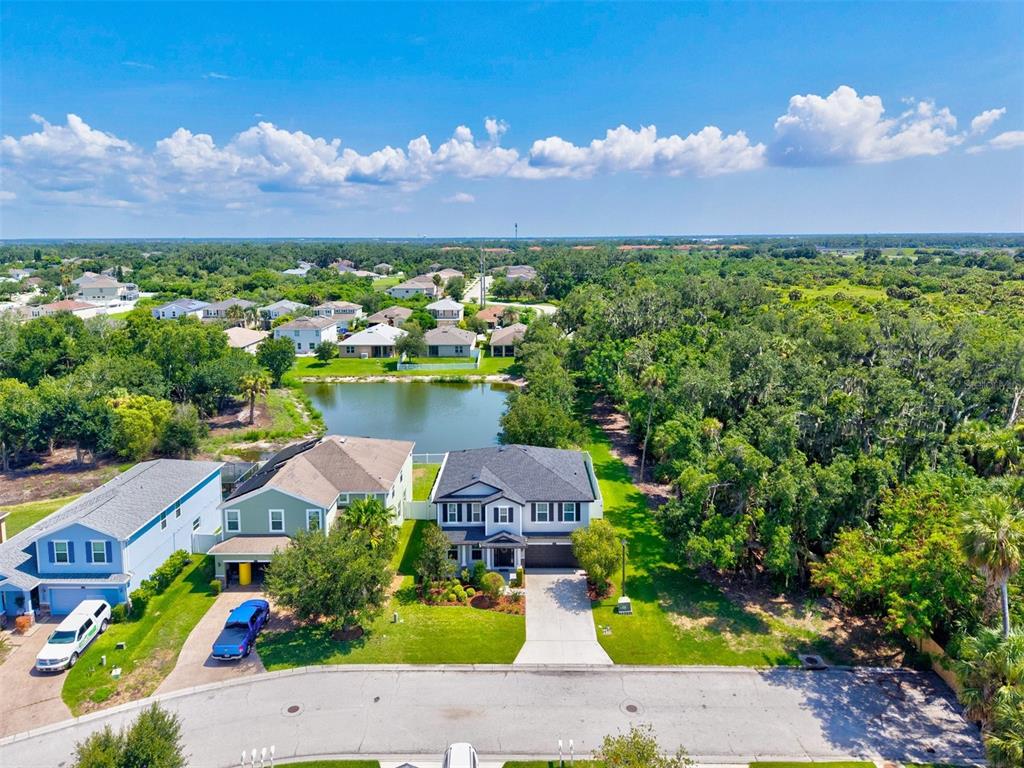 An aerial view shows a two-story house with a driveway next to a pond — 5703 NEW PARIS WAY, ELLENTON, FL