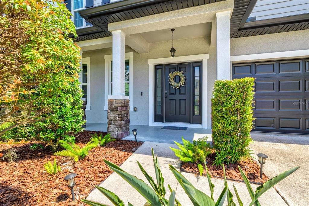 A front entryway features a dark door with sidelights, stone pillar accents, and landscaped beds — 5703 NEW PARIS WAY, ELLENTON, FL