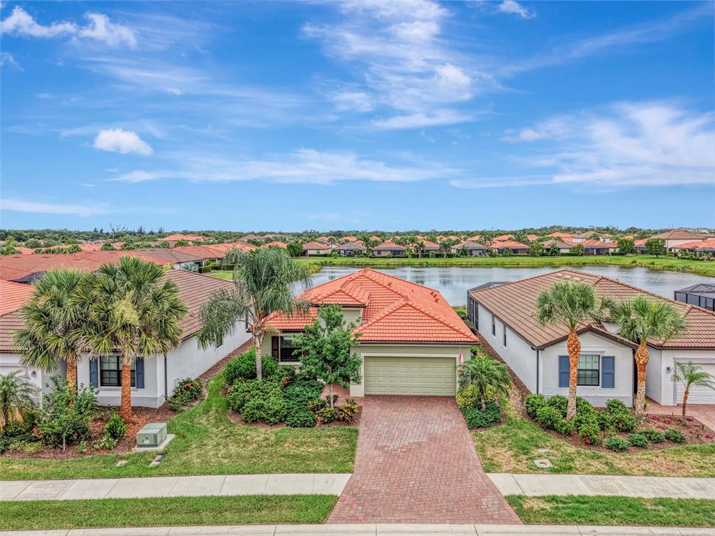 An aerial view of a suburban house with a tile roof and a brick driveway — 9903 WINGOOD DRIVE, VENICE, FL