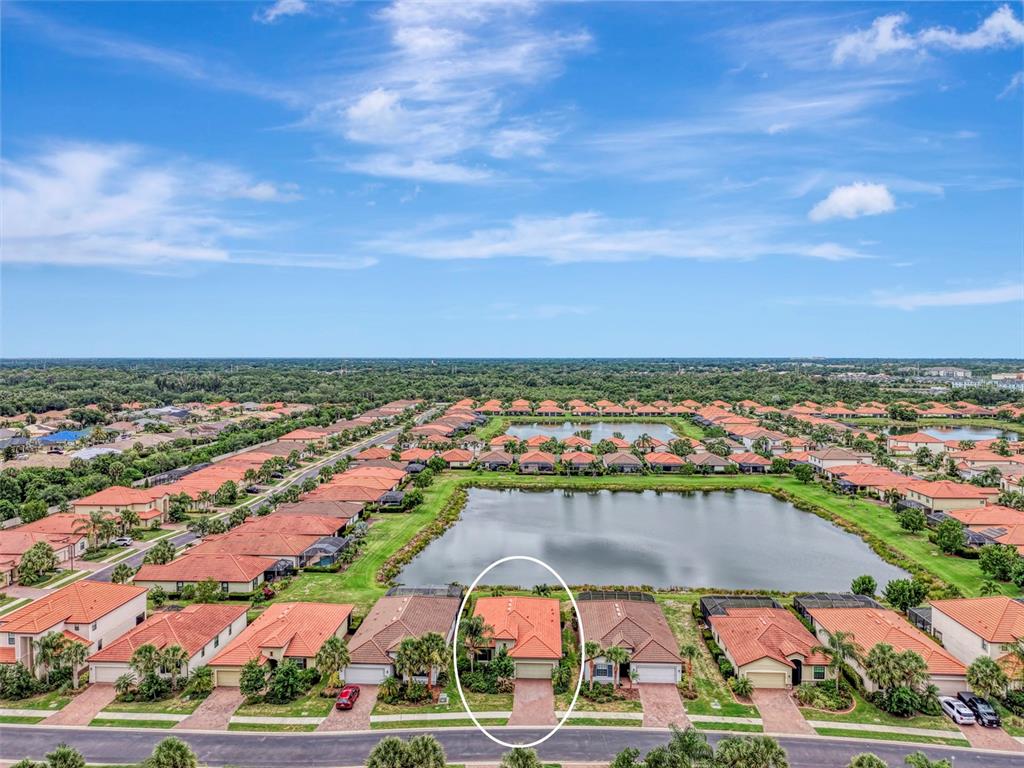 An aerial view shows a residential neighborhood with a lake and a circled house — 9903 WINGOOD DRIVE, VENICE, FL