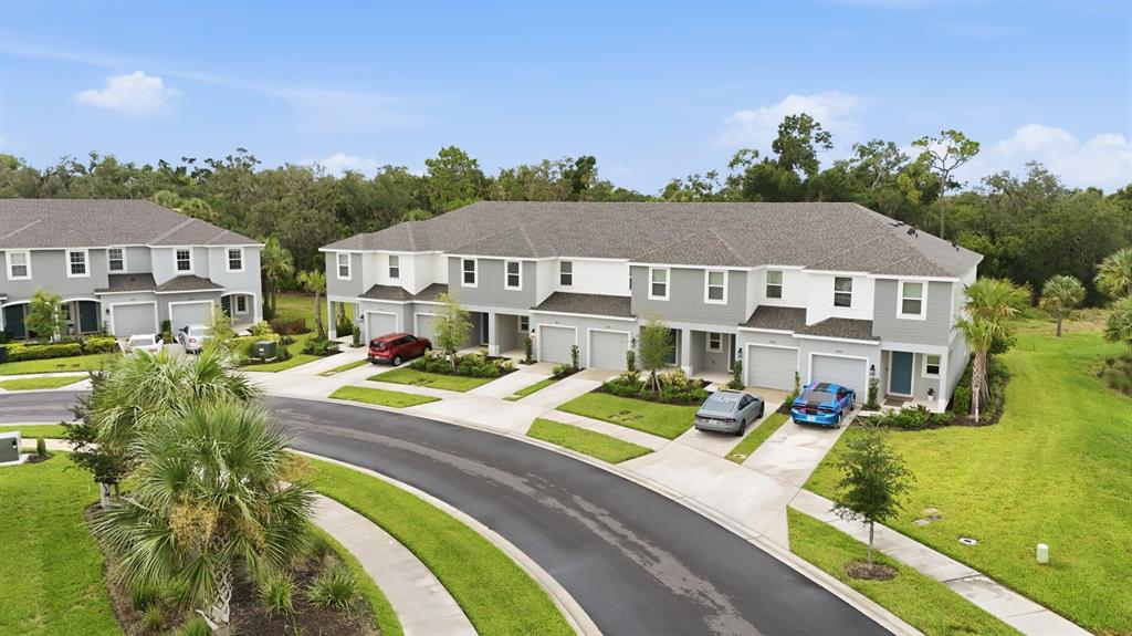 An aerial view shows a row of gray townhouses with attached garages and paved driveways — 8417 LUNAR SKYE STREET, SARASOTA, FL