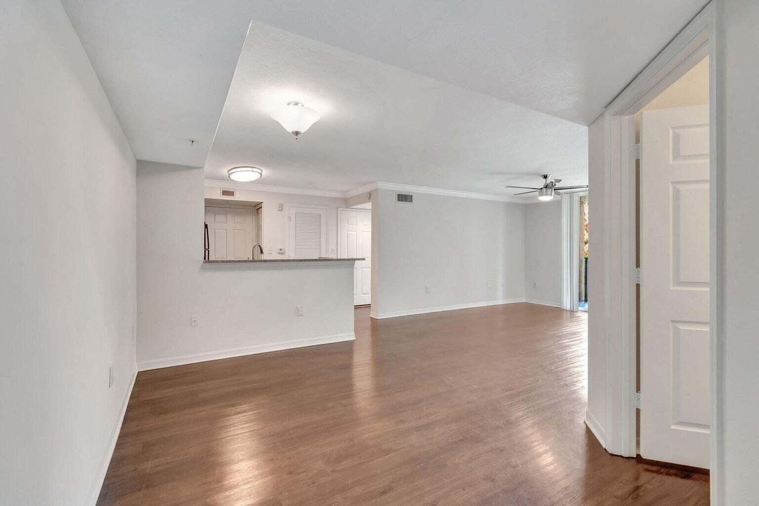 An open-concept living area features light-colored walls, wood-look flooring, and a kitchen breakfast bar — 15155 Michelangelo Boulevard # 106, Delray Beach FL 33446, DELRAY BEACH, FL
