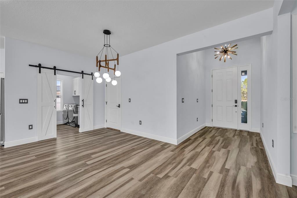 A bright entryway and dining area feature wood-look flooring, white walls, and a modern chandelier — 256 HIBISCUS LANE, POINCIANA, FL