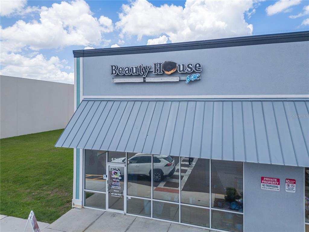 An exterior view of a commercial building storefront with a metal awning and signage — 1359 E OSCEOLA PARKWAY, KISSIMMEE, FL