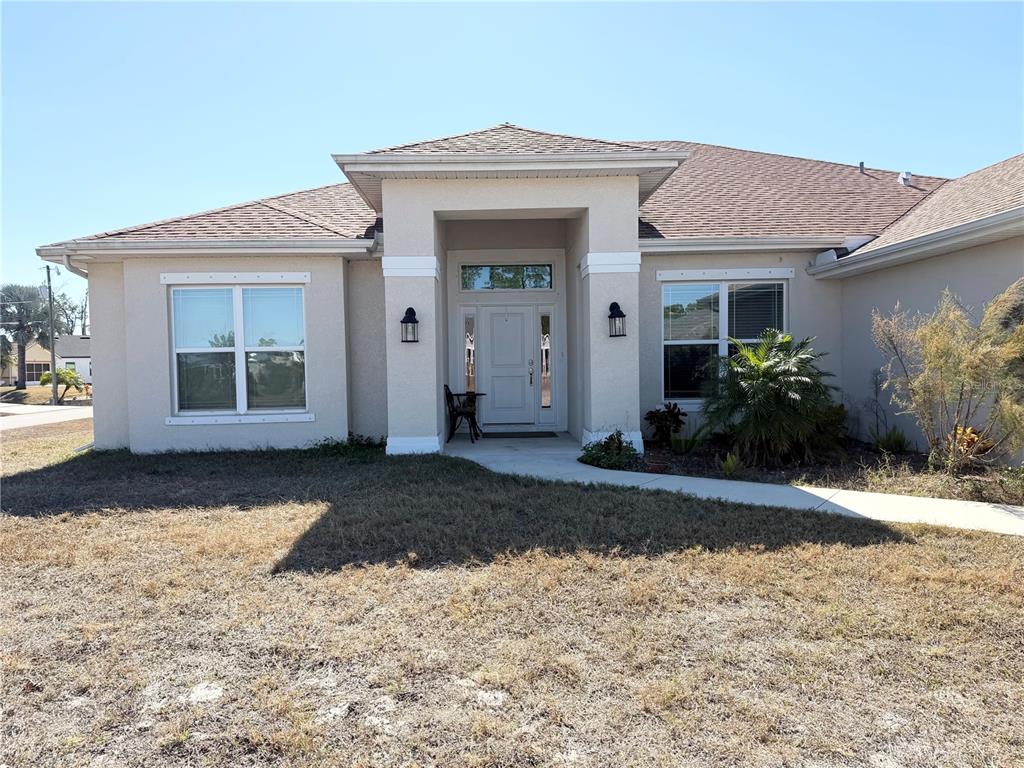 A beige single-story house features a covered entryway, a white front door, and two windows — 2779 STARVIEW AVENUE, NORTH PORT, FL