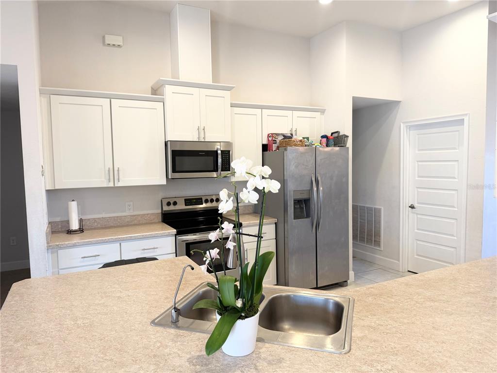 A kitchen features white cabinets, stainless steel appliances, and a central island with a sink — 2779 STARVIEW AVENUE, NORTH PORT, FL
