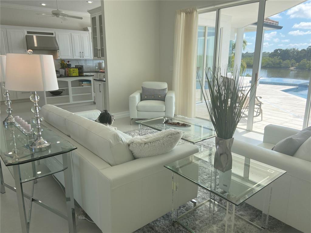 A bright living room features white leather furniture, glass tables, and a view of a pool — 3840 RUDDER WAY, NEW PORT RICHEY, FL