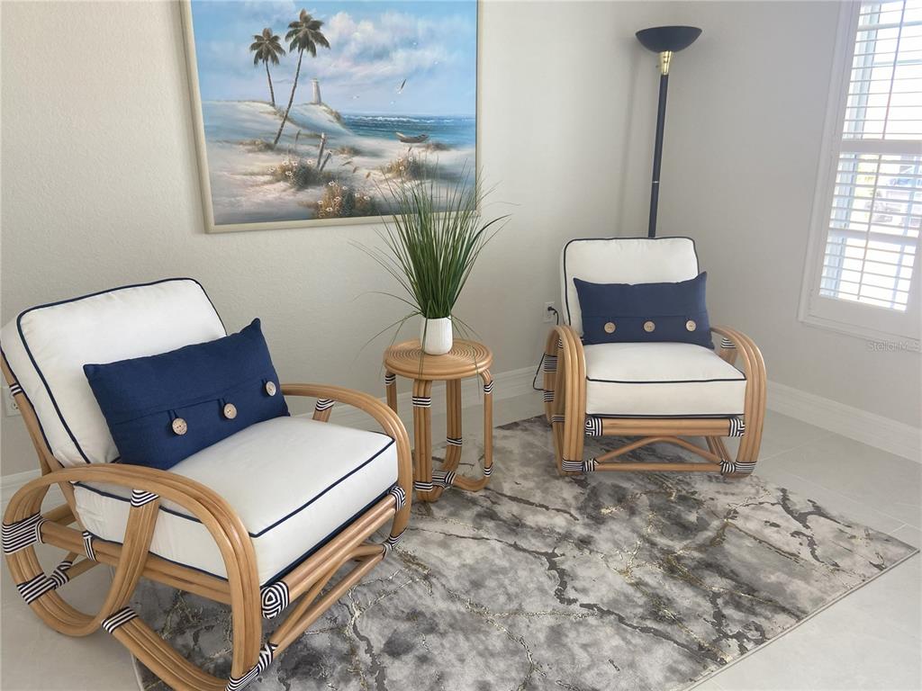 Two rattan chairs with white cushions and blue pillows sit on a gray rug — 3840 RUDDER WAY, NEW PORT RICHEY, FL