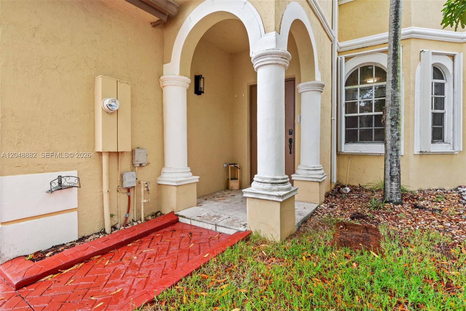 A tan stucco house exterior features a red brick walkway leading to a columned entryway — 4939 SW 136th Ave, Miramar FL 33027, MIRAMAR, FL