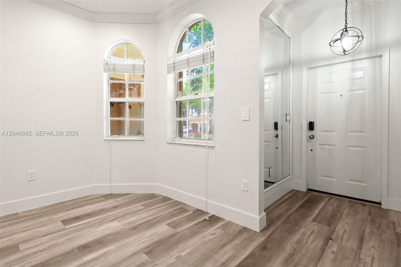 An entryway features wood-look flooring, arched windows, a mirrored wall, and a pendant light — 4939 SW 136th Ave, Miramar FL 33027, MIRAMAR, FL