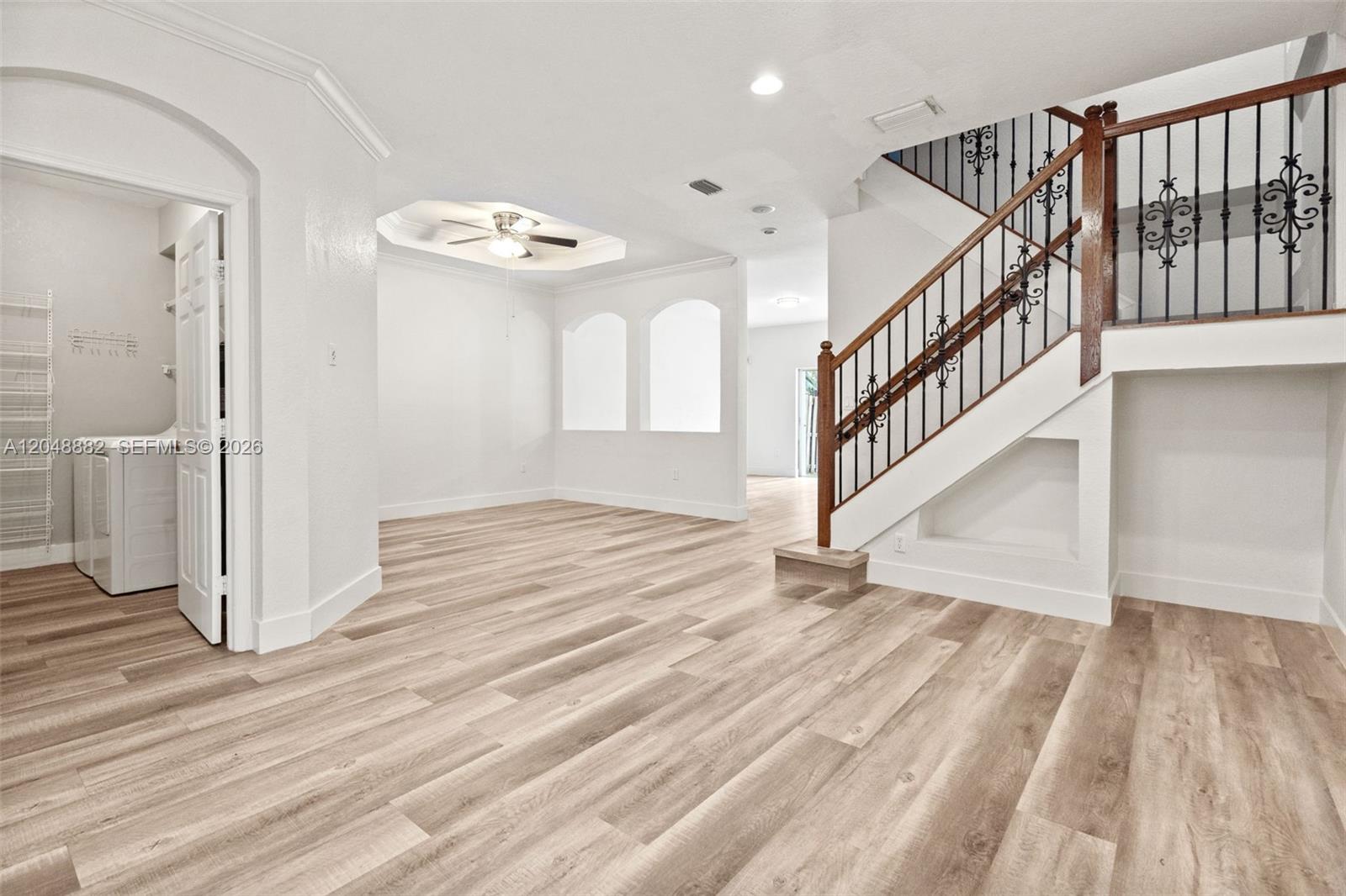 An open living area features light wood-look flooring, a staircase with iron railings, and arched alcoves — 4939 SW 136th Ave, Miramar FL 33027, MIRAMAR, FL