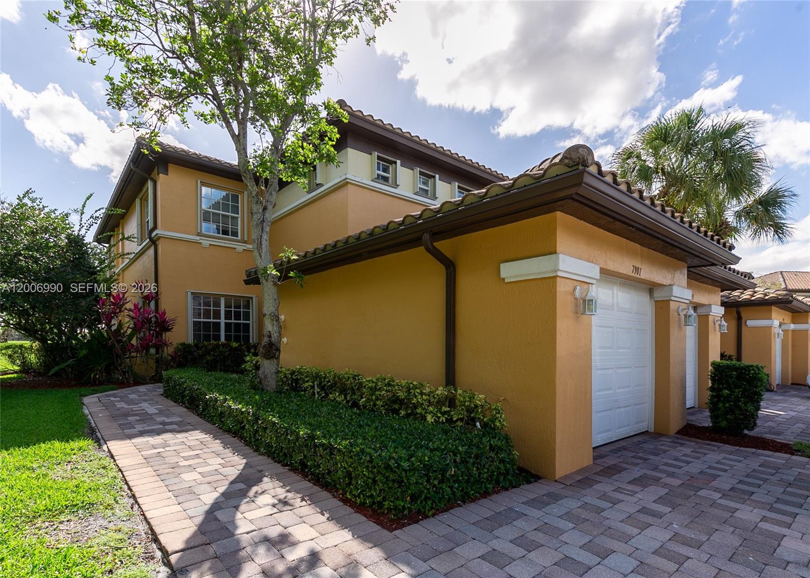 A two-story stucco townhouse with a tiled roof, attached garages, and a paved driveway — 7901 NW 128th Ln # A, Parkland FL 33076, PARKLAND, FL