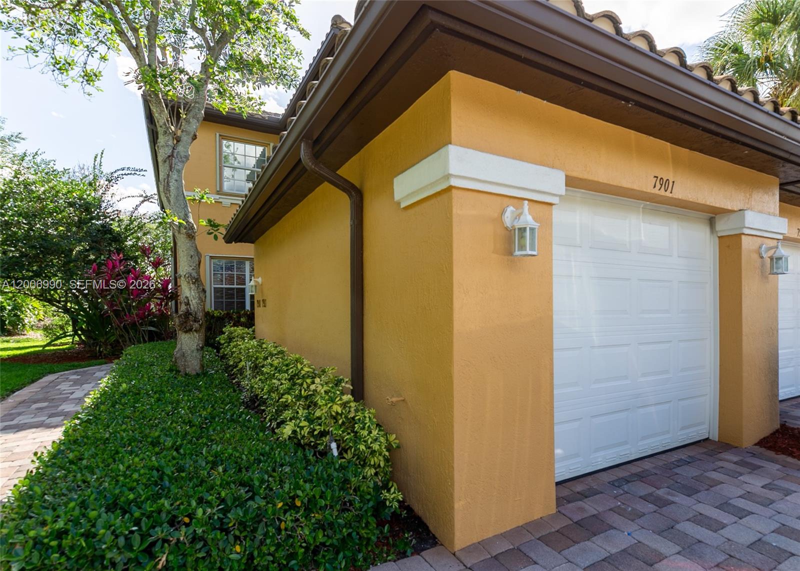 A two-story yellow stucco house features a tile roof, a brick walkway, and a garage — 7901 NW 128th Ln # A, Parkland FL 33076, PARKLAND, FL