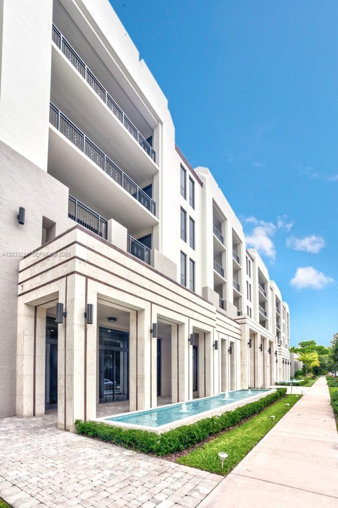 A modern multi-story apartment building features a long reflecting pool and landscaped walkway — 718 Valencia Ave # 202, Coral Gables FL 33134, CORAL GABLES, FL