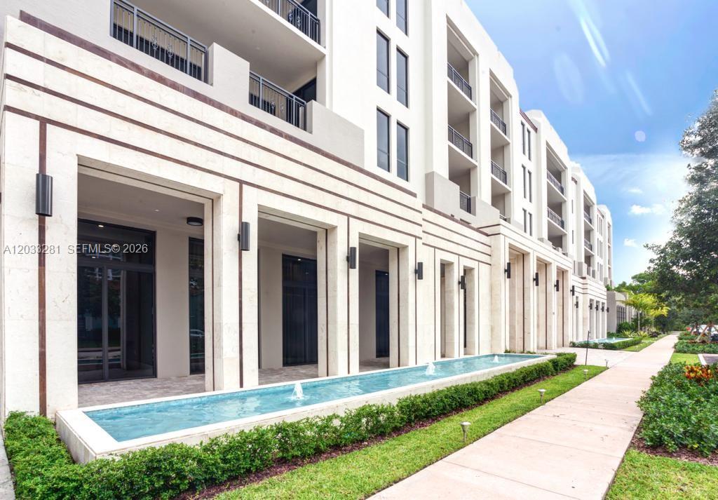 A multi-story building exterior features a long reflecting pool and a paved walkway — 718 Valencia Ave # 202, Coral Gables FL 33134, CORAL GABLES, FL
