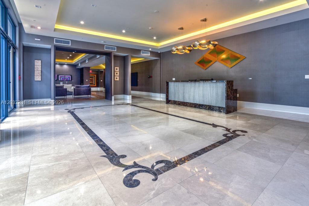 A modern lobby features a marble floor with a dark inlay, reception desk, and recessed lighting — 718 Valencia Ave # 202, Coral Gables FL 33134, CORAL GABLES, FL