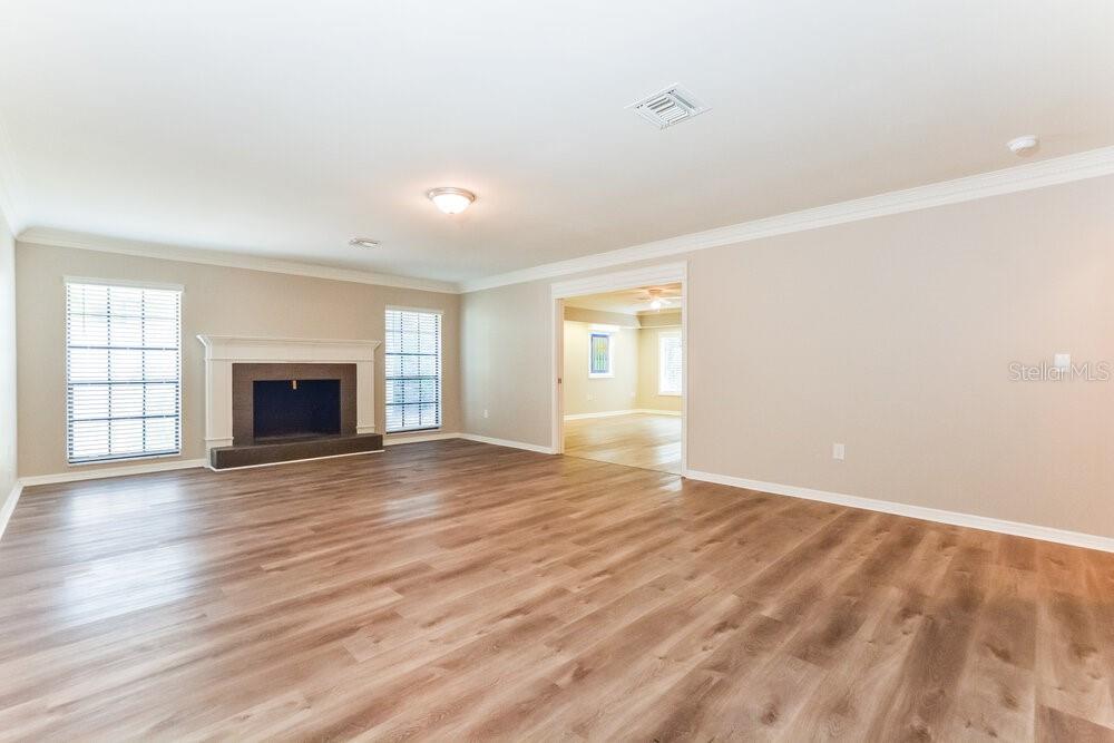A spacious living room features light wood-look flooring, a fireplace, and an adjacent room entrance — 51 DOGWOOD LANE, EUSTIS, FL