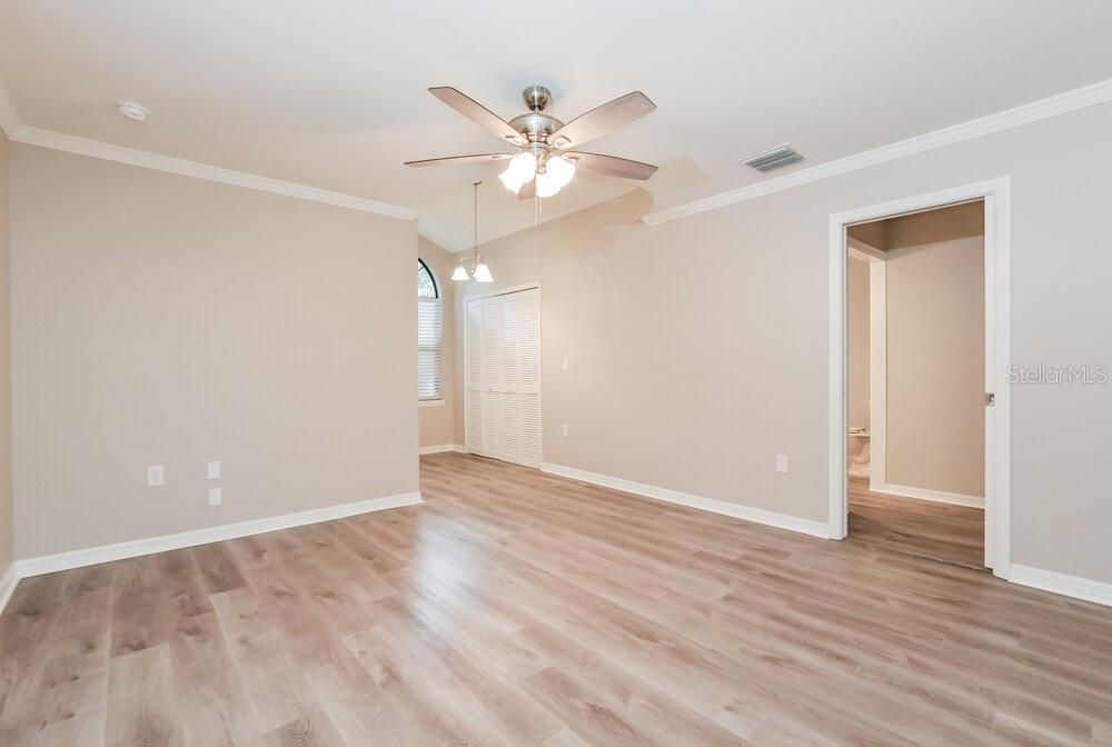 An empty room features light-colored walls, wood-look flooring, a ceiling fan, and a doorway — 51 DOGWOOD LANE, EUSTIS, FL