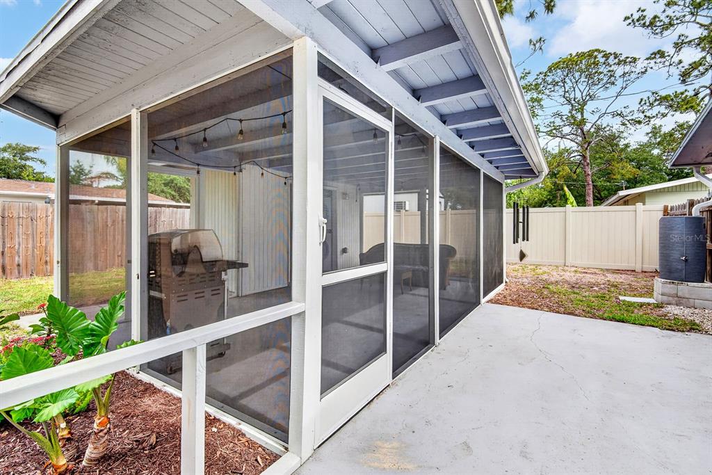 A screened-in porch with a concrete floor, a grill, and a white fence in the background — 916 PATTISON AVENUE, SARASOTA, FL