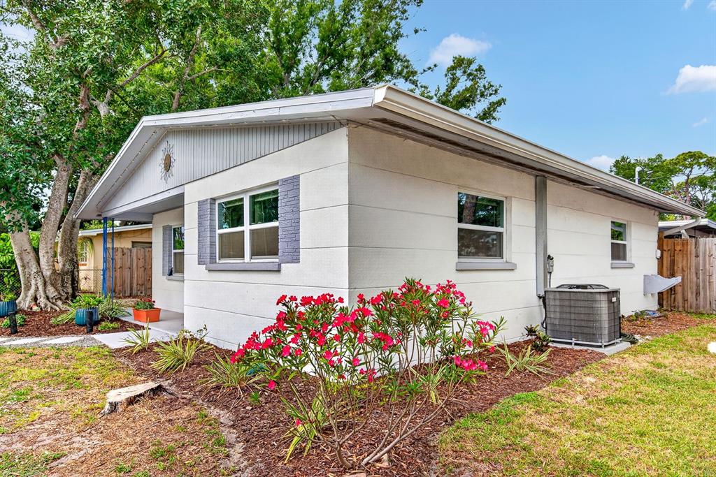 A white, single-story house with a gray gable roof and a red-flowering bush outside — 916 PATTISON AVENUE, SARASOTA, FL