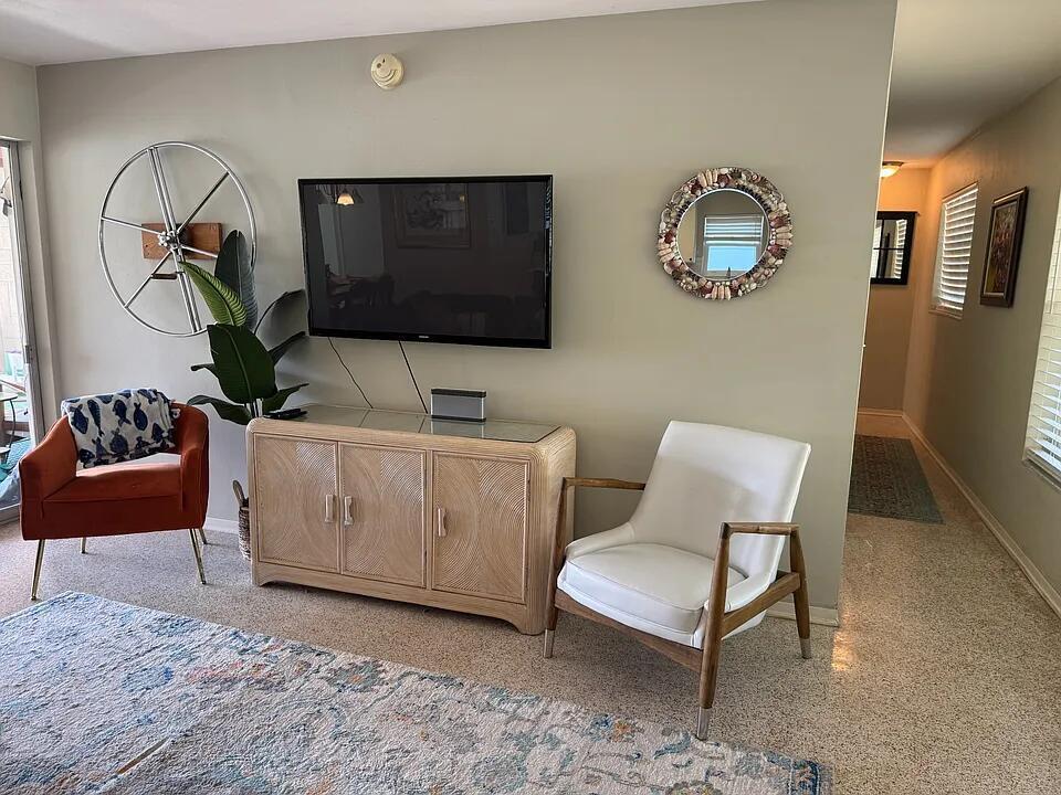 A living room features a wall-mounted television, a rattan console, and two accent chairs — 1511 Seabrook Road, Jupiter FL 33469, JUPITER, FL