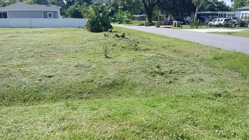 A grassy, mowed vacant lot sits next to a paved road in a residential neighborhood — 2778 TROPICAL LAKE DRIVE, KISSIMMEE, FL