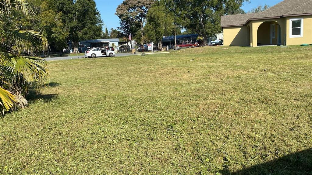 A grassy, vacant lot sits in front of a tan house with a palm tree nearby — 2778 TROPICAL LAKE DRIVE, KISSIMMEE, FL