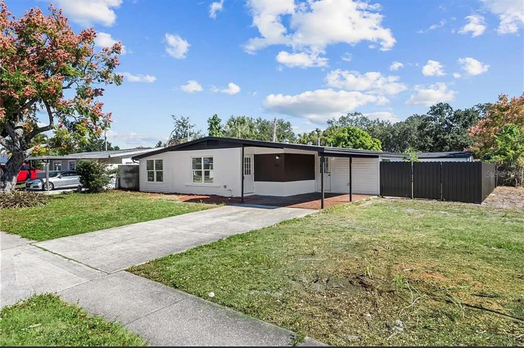 A single-story white house with a dark roof, a carport, and a concrete driveway — 5101 TOWN N COUNTRY BOULEVARD, TAMPA, FL