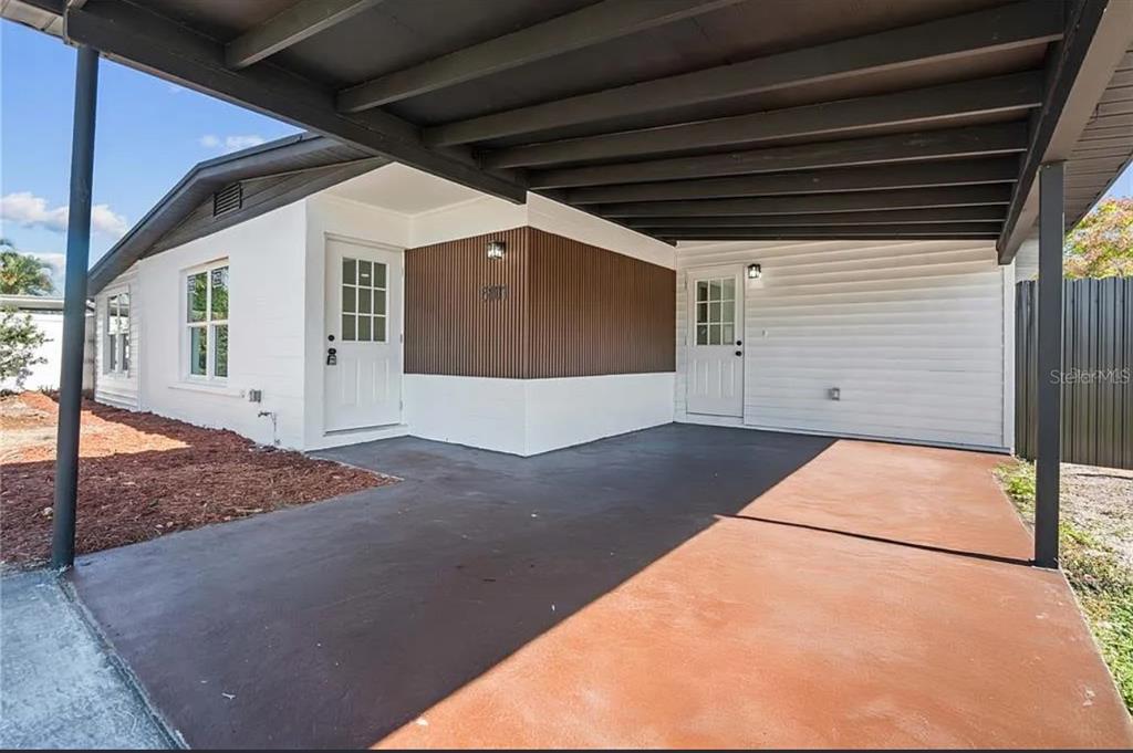 A covered carport area features a concrete floor, white siding, and brown vertical accent paneling — 5101 TOWN N COUNTRY BOULEVARD, TAMPA, FL