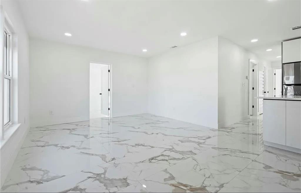 An open-concept room with white walls, recessed lighting, and large white marble-patterned floor tiles — 5101 TOWN N COUNTRY BOULEVARD, TAMPA, FL