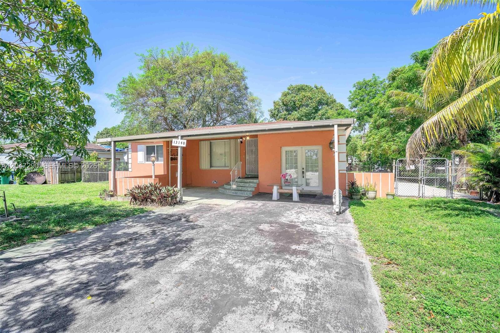 A single-story peach-colored house features a concrete driveway, a covered porch, and a fenced yard — 13140 N Miami Ave # 1, Miami FL 33168, MIAMI, FL