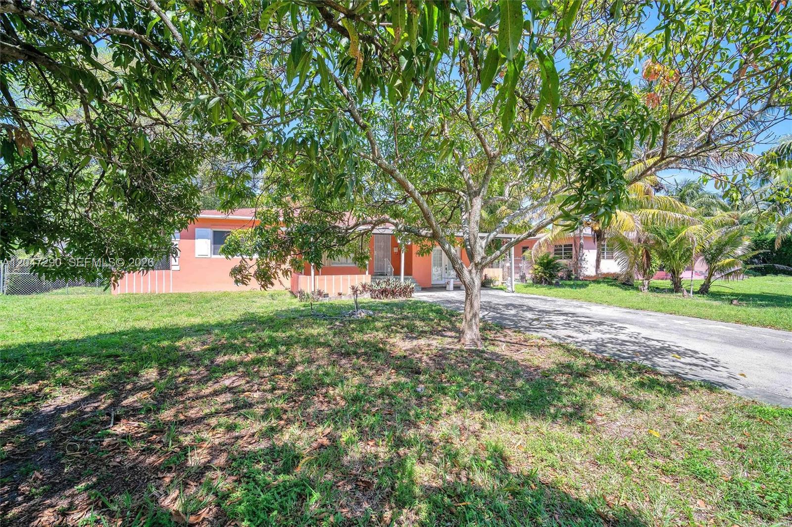 A single-story peach-colored house with a driveway sits behind a large tree — 13140 N Miami Ave # 1, Miami FL 33168, MIAMI, FL