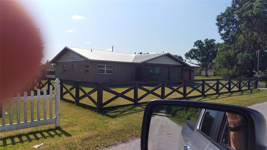 A single-story house with a metal roof and a black wooden cross-buck fence — 3008 N MARYLAND AVENUE, PLANT CITY, FL