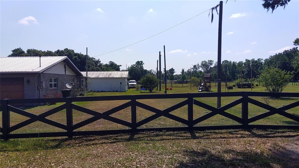 A black wooden fence encloses a grassy yard with a house, shed, and playground equipment — 3008 N MARYLAND AVENUE, PLANT CITY, FL