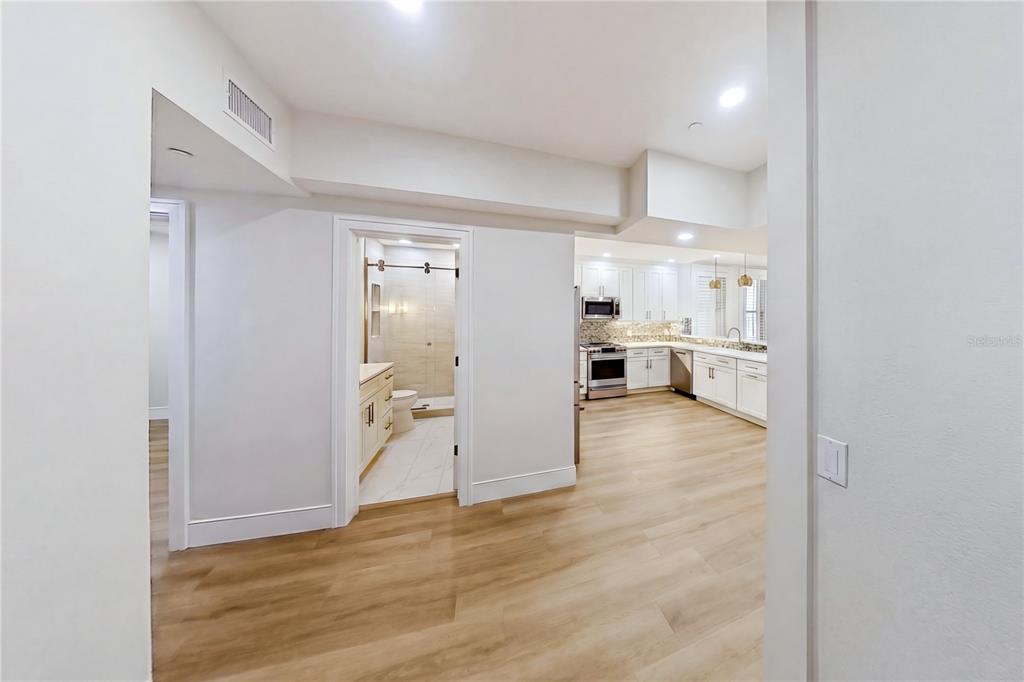 A view from a hallway looking into a bathroom and an open-concept kitchen — 1221 N PALM AVENUE UNIT 106/107, SARASOTA, FL