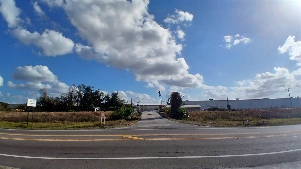 A paved road leads toward a large industrial building under a blue, cloudy sky — 2295 US HIGHWAY 92 E, PLANT CITY, FL