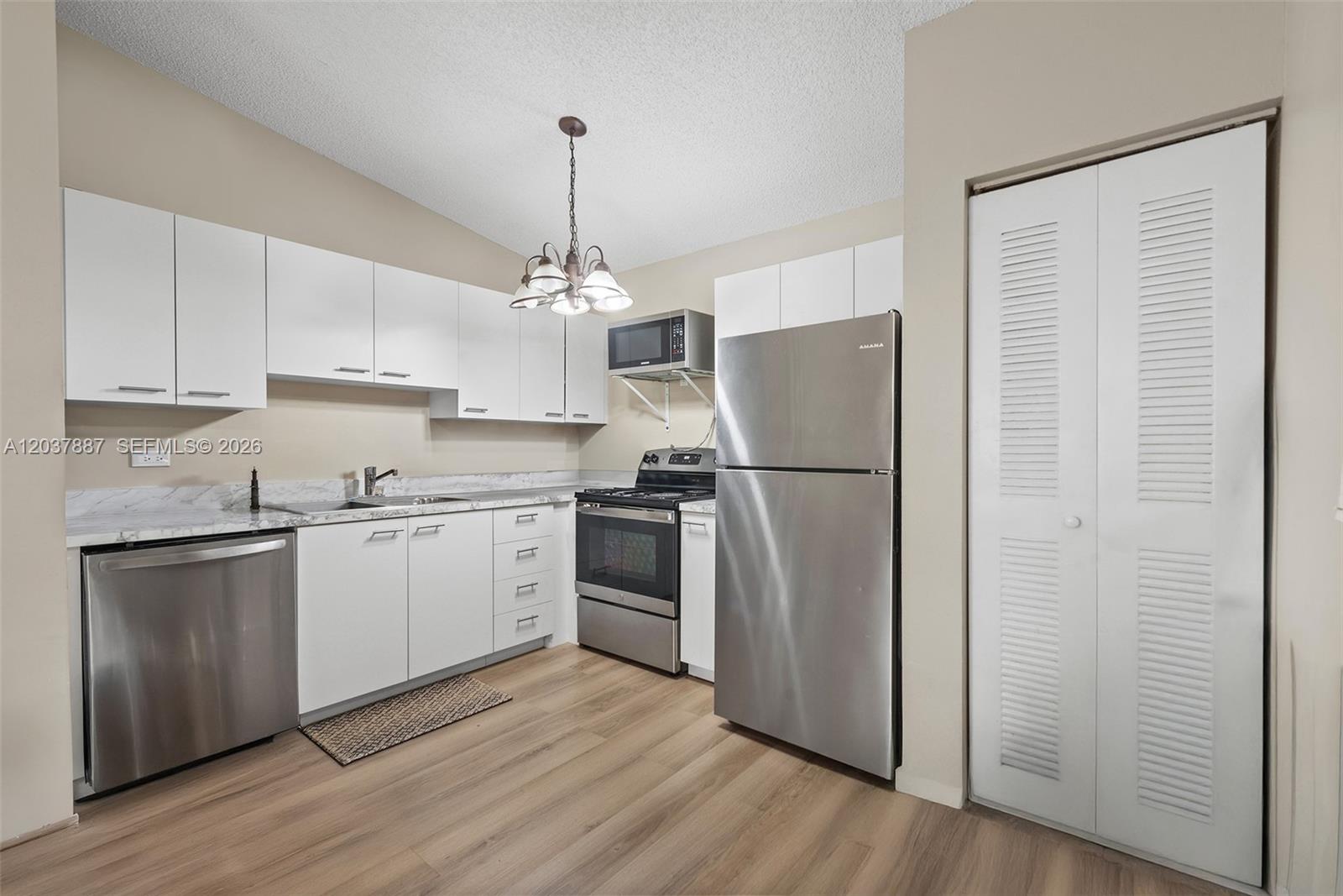 This kitchen features white cabinets, stainless steel appliances, and wood-look flooring — 3690 N 56th Ave # 948, Hollywood FL 33021, HOLLYWOOD, FL