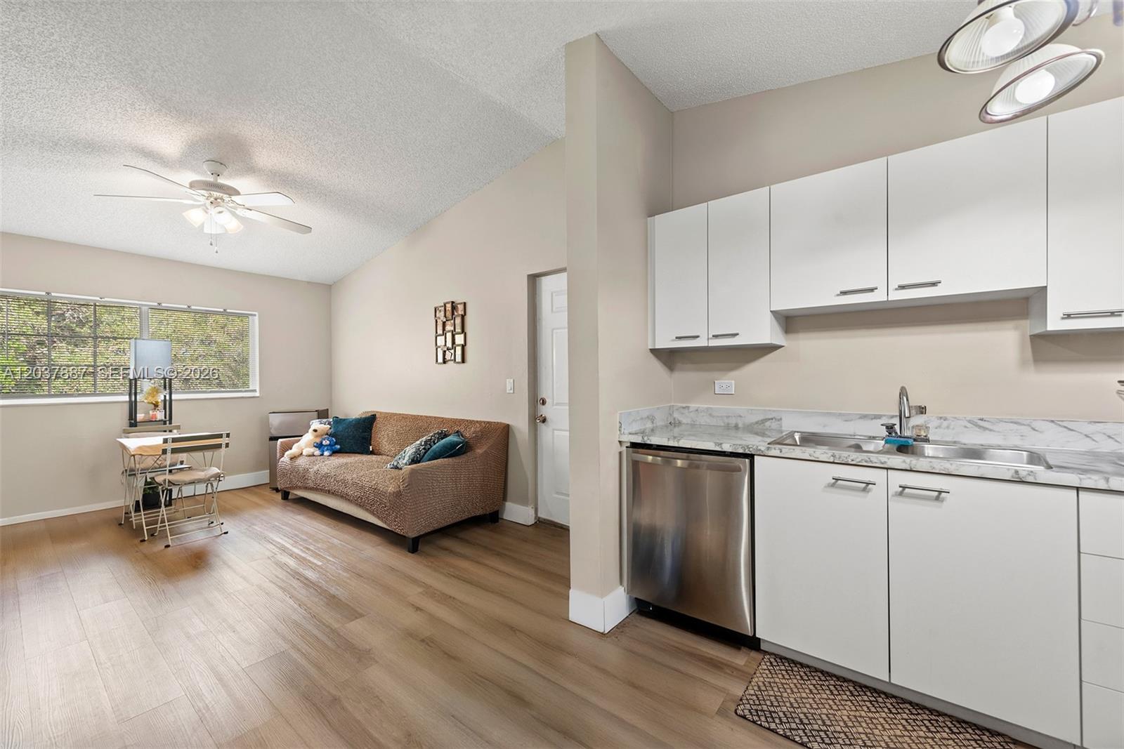 A studio apartment features a kitchenette with white cabinets and a living area with wood-look flooring — 3690 N 56th Ave # 948, Hollywood FL 33021, HOLLYWOOD, FL