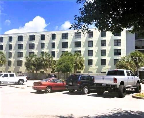A multi-story apartment building stands behind a parking lot with several vehicles — 701 S MADISON AVENUE UNIT 106, CLEARWATER, FL