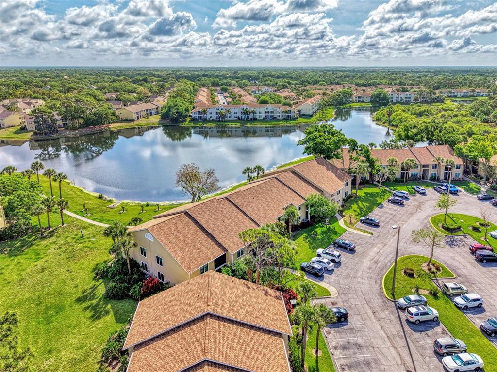An aerial view shows apartment buildings surrounding a lake with a parking lot in front — 4045 CROCKERS LAKE BOULEVARD UNIT 11, SARASOTA, FL