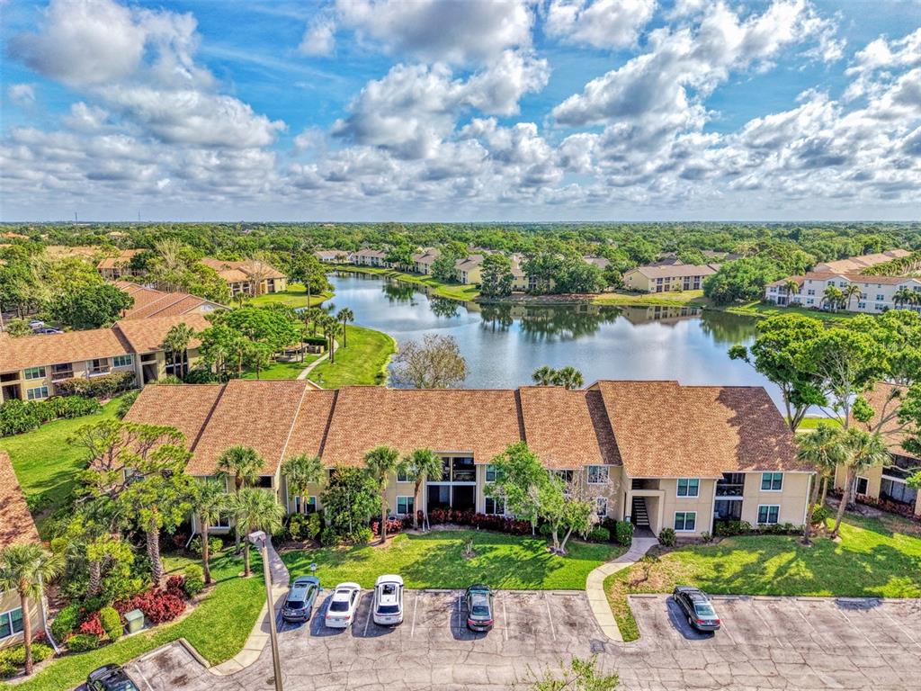An aerial view of a multi-story apartment complex with a lake and parking lot — 4045 CROCKERS LAKE BOULEVARD UNIT 11, SARASOTA, FL