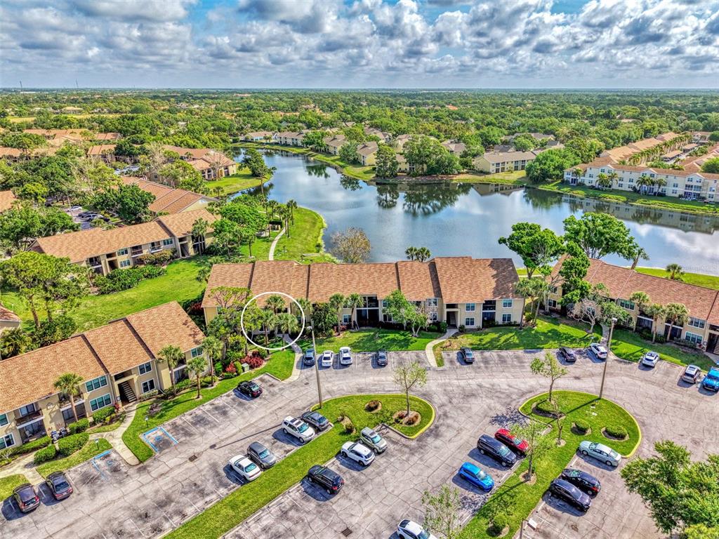 An aerial view of a multi-story apartment complex with a lake and parking lot — 4045 CROCKERS LAKE BOULEVARD UNIT 11, SARASOTA, FL